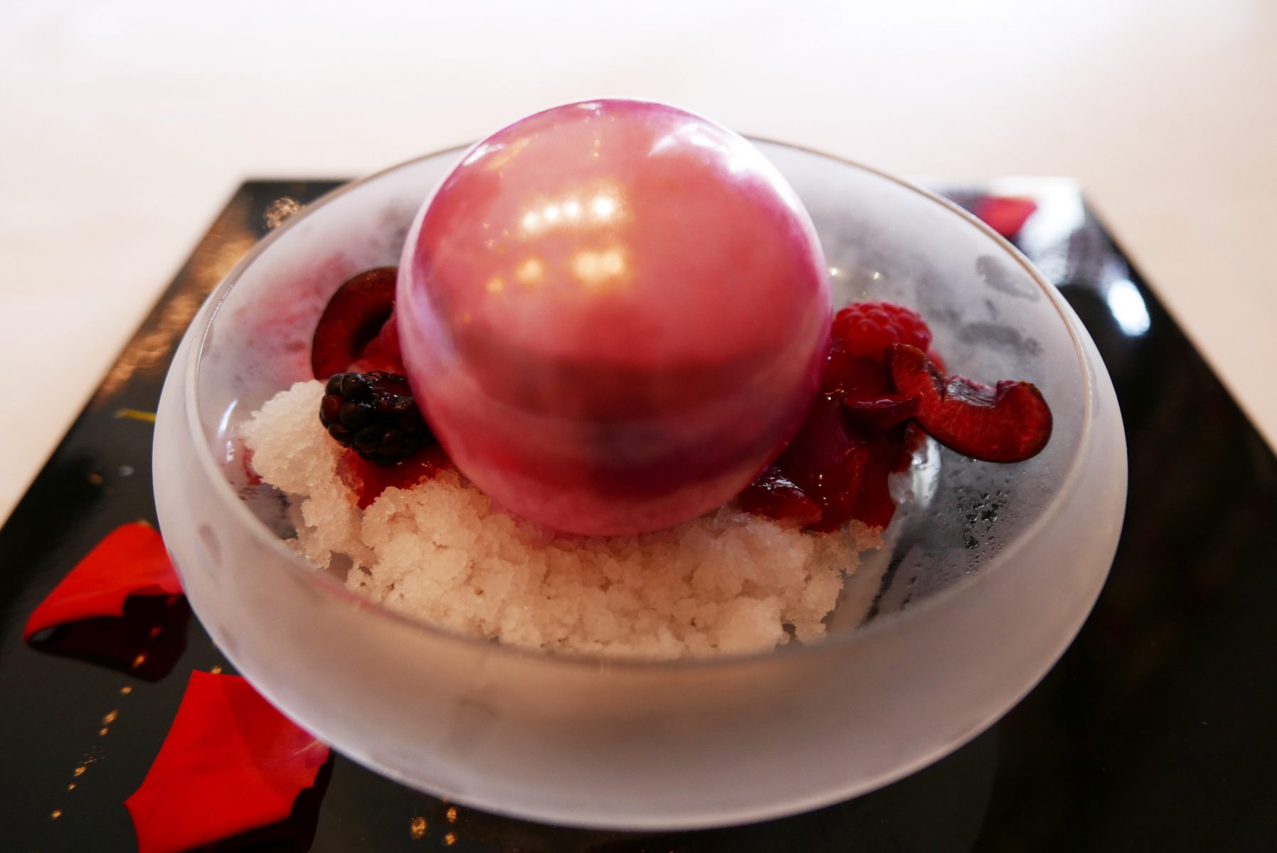 Sugar ball with red berries, filled up with lychee and vanilla cream,