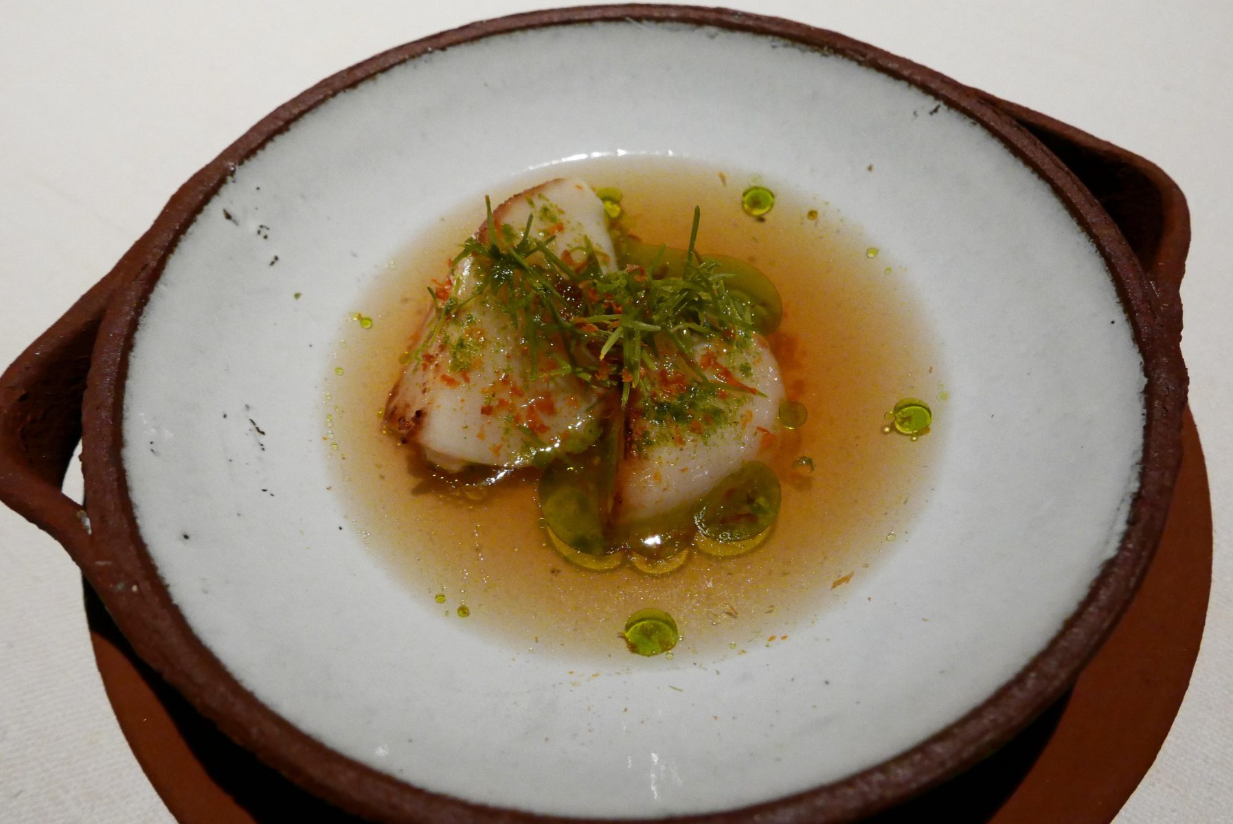 Seared live scallop in "dashi" with finger lime and spruce tips