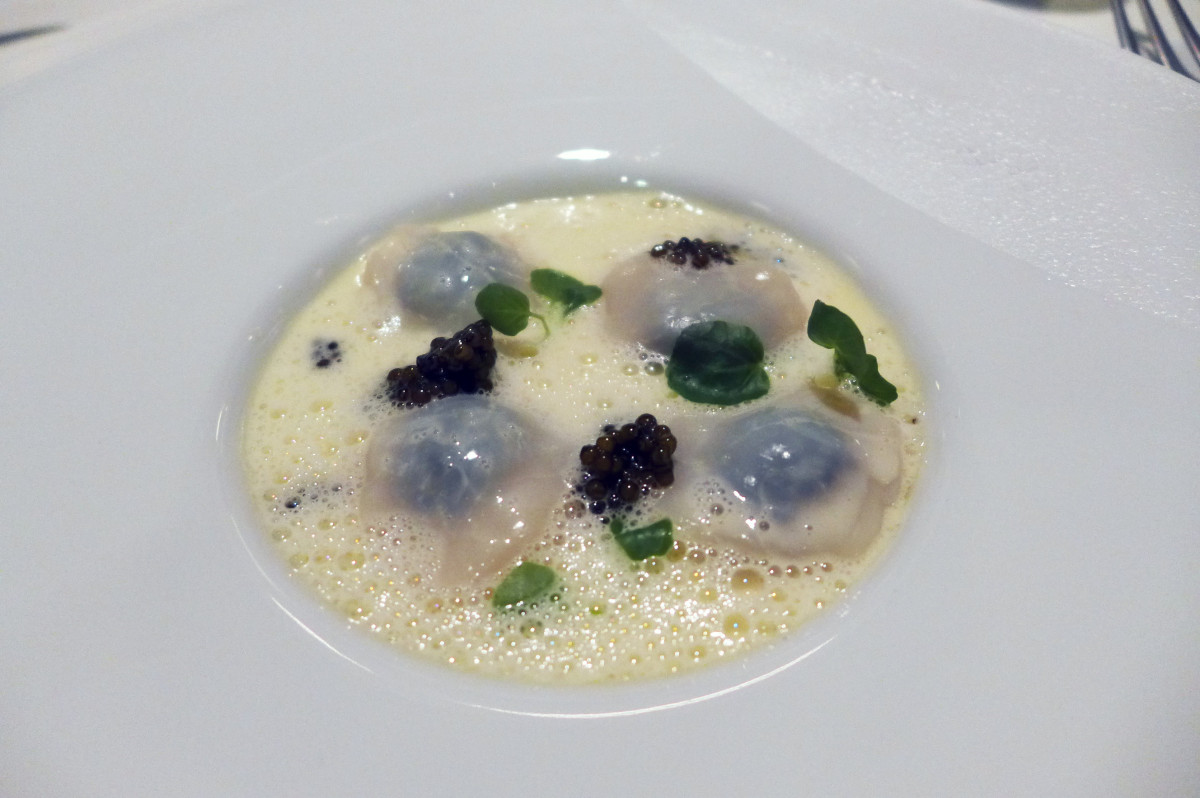 Raw scallops stuffed with black caviar in butter sauce